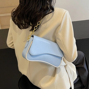 Moderne hellblaue Achseltasche mit gewellten Kanten und Goldkette an weiblichem Modell