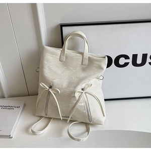 Detail of cream backpack with ribbon bows and marble texture synthetic leather finish