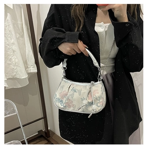 Detail of floral jacquard embroidery with silver leather trim and chain strap on handbag