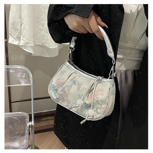 Detail of floral embroidery on jacquard fabric handbag with silver metallic trim and chain