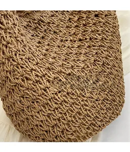 Gros plan détaillé montrant le motif de tissage ajouré du sac seau en paille tressée