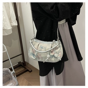 Model wearing a small square crossbody bag with oriental embroidery and metal handle