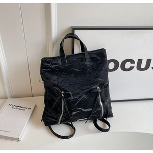 Detail of black pleated tote bag featuring decorative bow ties and silver brand logo