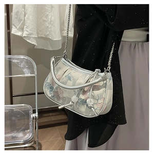 Detailed close-up of Chinese style floral jacquard fabric and silver chain strap on bag