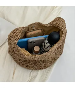 Vue de l'intérieur spacieux du sac seau en paille avec téléphone, portefeuille et parapluie