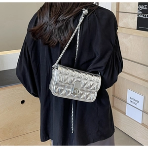 Close-up of a silver quilted chain bag featuring a metallic finish and a twist-lock clasp