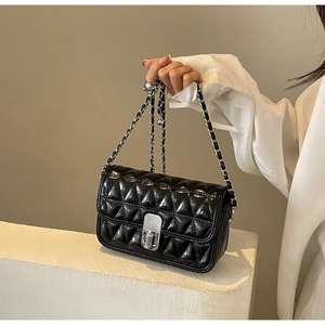 Close-up of black quilted chain bag featuring a silver metal twist-lock and glossy finish