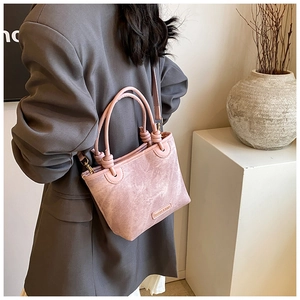 Pink retro textured bucket bag with unique knotted handle detail worn over a grey blazer