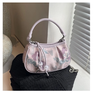Detailed macro view of floral jacquard texture and silver chain on purple handbag