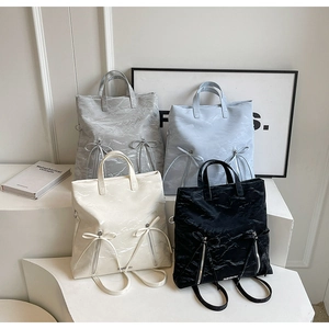 Detail view of stylish tote backpacks in four colors with decorative bows and pockets