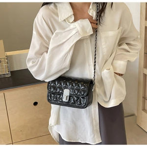 Detail of black quilted leather shoulder bag with silver clasp and chain strap