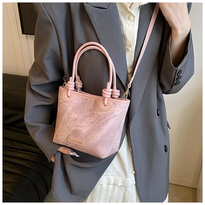 Detail of pink bucket bag with knotted handles and fashion logo on matte fabric