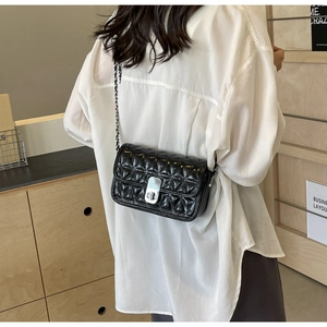 Detailed back view of a woman wearing the quilted black chain crossbody bag