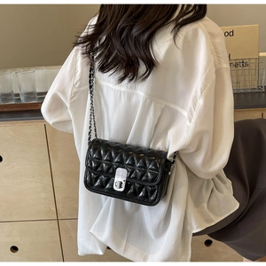 Detail of a black quilted chain bag with glossy finish on a model for a stylish back view