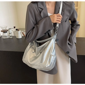 Chic silver metallic hobo bag with adjustable strap worn with a grey blazer for a modern look