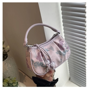 Detailed close-up of light purple canvas handbag with floral embroidery and beaded tassel