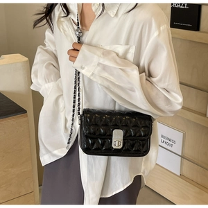 Detail view of black quilted crossbody bag with silver twist lock and chain strap