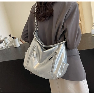Silver metallic oversized hobo tote bag with zipper details worn by a model