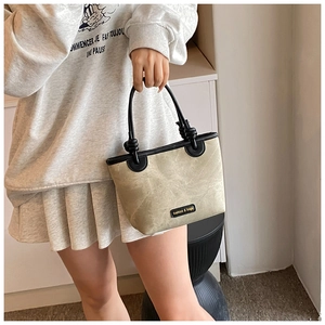 Detail of khaki bucket bag with black leather handle and knot design for daily wear