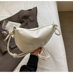 Detail of white half-moon shoulder bag with elegant knot metal hardware accents