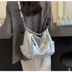 Macro detail of large silver metallic hobo bag with zip pockets shown on model