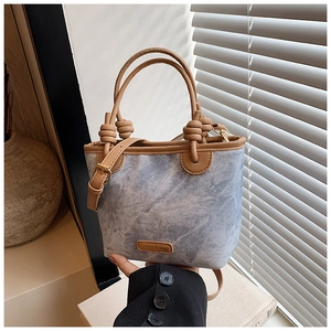 Detail of denim bucket bag with leather handles and knot design for women