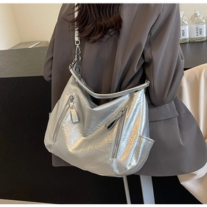 Silver hobo shoulder bag with double zipper details on textured shiny metallic material