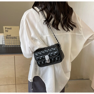 Quilted black leather crossbody bag with silver chain strap shown in a lifestyle setting