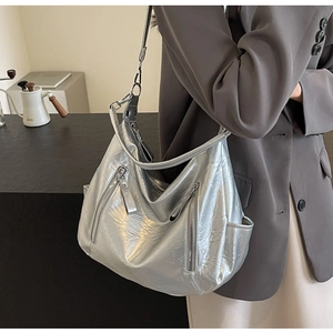 Silver metallic hobo bag with pleated texture and vertical zippers shown on shoulder
