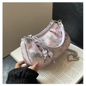 Detail of lavender floral embroidery on a purple crescent handbag with silver chain strap