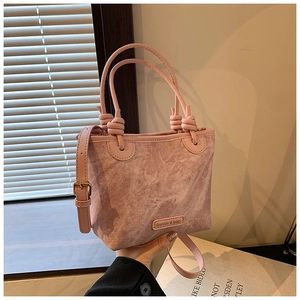 Detail of pink textured bucket bag with unique knotted handle and adjustable leather strap