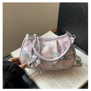Detail of lavender floral jacquard handbag with braided knot handle on an open book