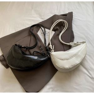 Detail of minimalist crescent shoulder bags in black and cream with knot strap accents