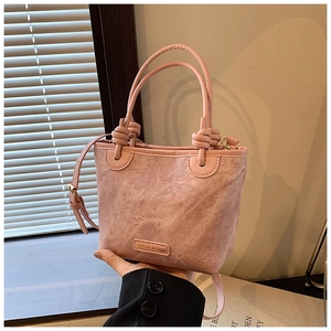 Close-up of pink bucket bag with unique knot handles and textured fabric detail