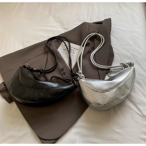 Detail of minimalist crescent shoulder bags in black and silver on a brown blazer