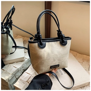 Detail of minimalist beige bucket bag with knotted handles and black leather piping