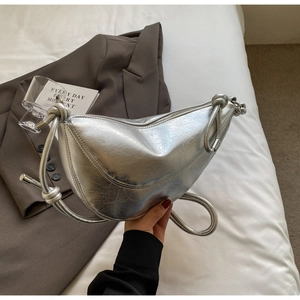 Detail of silver crescent moon bag with metallic crinkled texture and knot strap accents