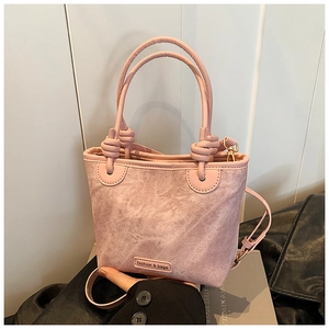 Detail of pink denim texture bucket bag featuring knotted handle and gold metal hardware