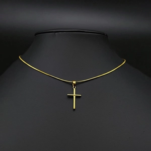 Collier croix minimaliste en acier inoxydable doré exposé sur un buste à bijoux noir