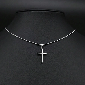Gros plan d'un pendentif croix argenté sur une chaîne serpent sur un buste noir