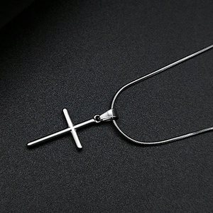 Collier avec pendentif croix en acier inoxydable poli et chaîne serpent sur fond noir