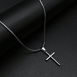 Pendentif croix en acier inoxydable poli avec chaîne serpent élégante sur fond noir mat