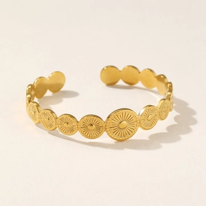Macro view of gold sunburst engraved round discs on stainless steel open cuff bracelet