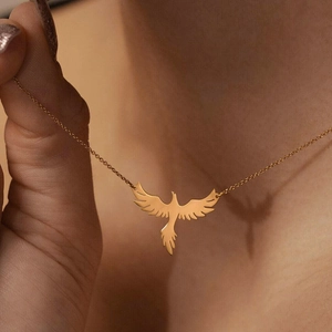 Détail d'un collier pendentif phénix doré sur une chaîne fine porté par une personne