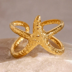 Détail de la bague étoile de mer dorée avec texture martelée et anneau croisé