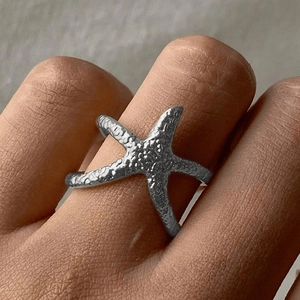 Détail d'une bague étoile de mer argentée avec texture bionique portée à la main