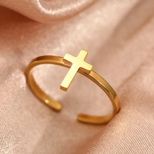 Polished gold stainless steel cross open ring for couples on peach silk fabric