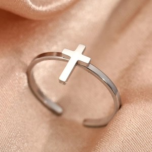 Polished silver stainless steel cross open ring on champagne silk fabric background
