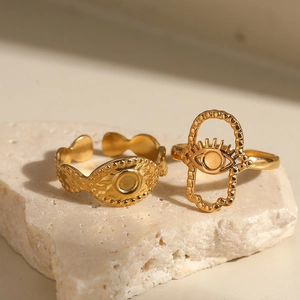 Detail of gold evil eye and Hamsa hand rings with textured finish on stone
