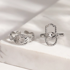 Silver Hamsa Hand and Evil Eye stainless steel rings set on white marble surface